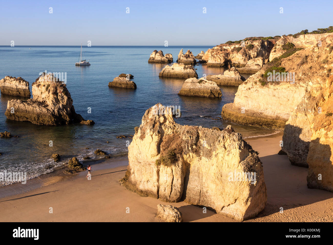 Runner on the fine sandy beach bathed by the blue ocean at dawn Praia do Alemao Portimao Faro district Algarve Portugal Europe Stock Photo