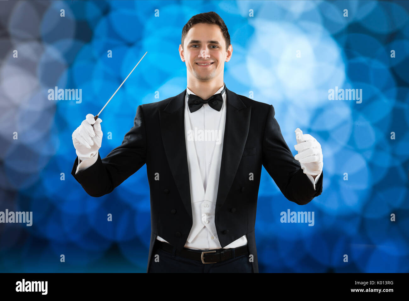 Portrait of happy music conductor holding baton against colored