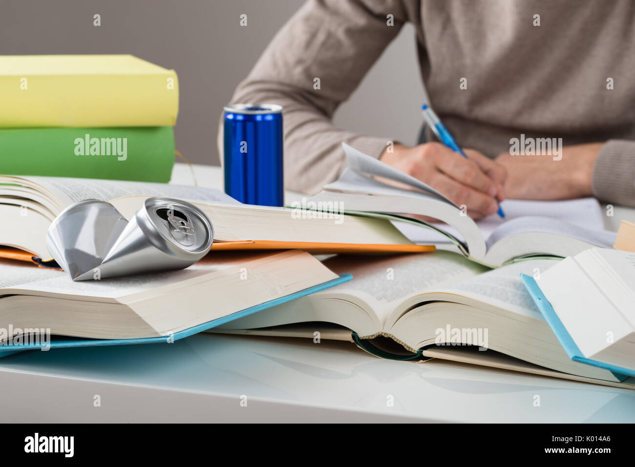 Midsection of male student studying with crashed drink can and books at table Stock Photo