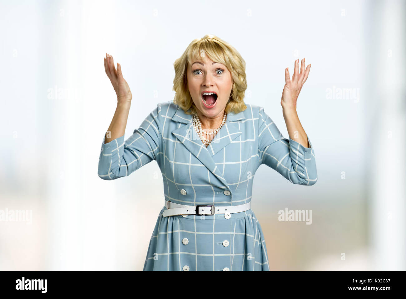 Surprised mature women raised hands. Adult woman with open mouth and eyes raised hands in confusion. Facial expression and body language. Stock Photo