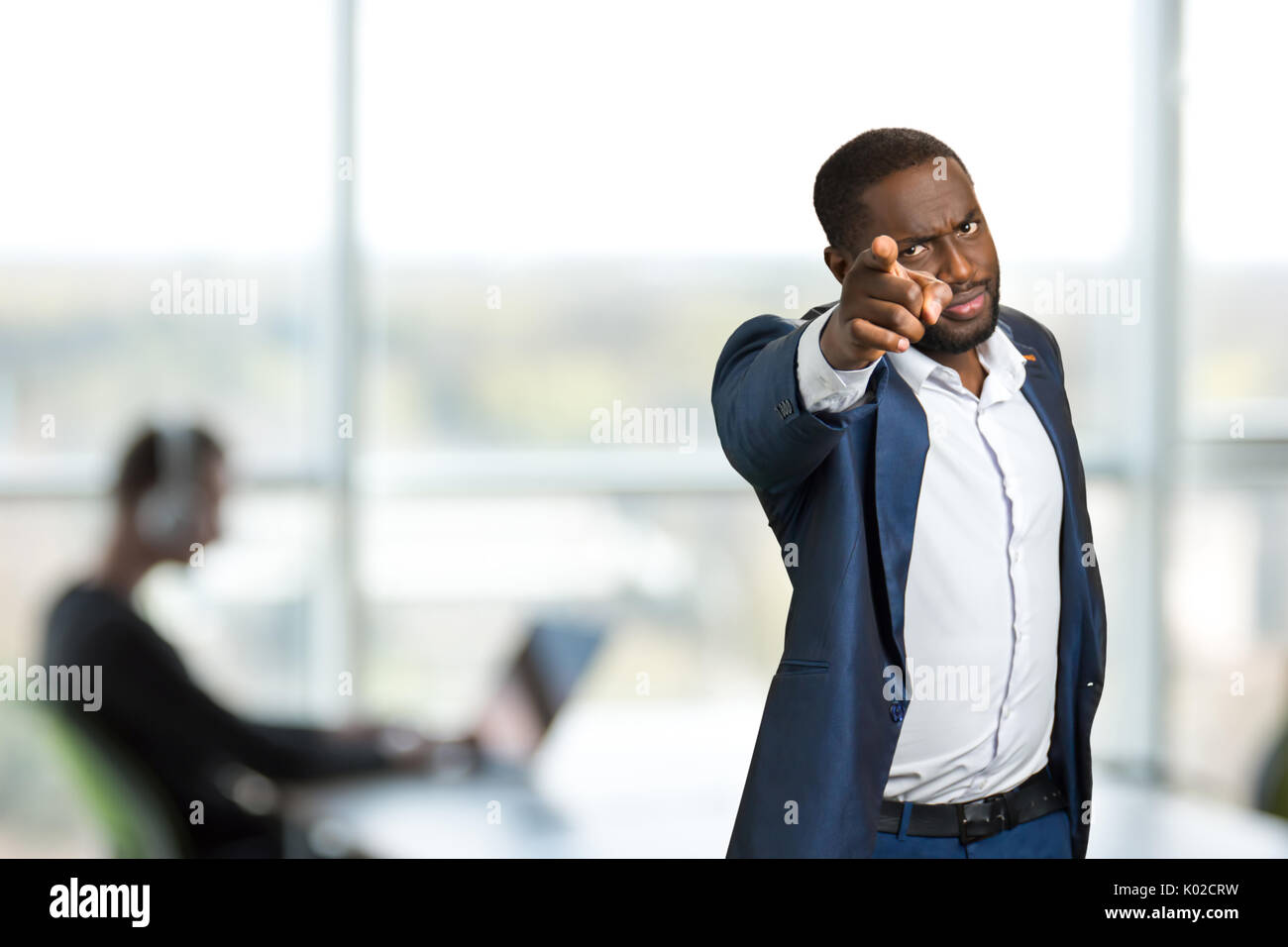 Serious businessman pointing forward. Black man in suit pointing