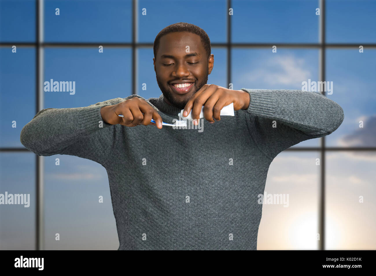 Black man applying toothpaste on a toothbrush. Smiling afro american ...