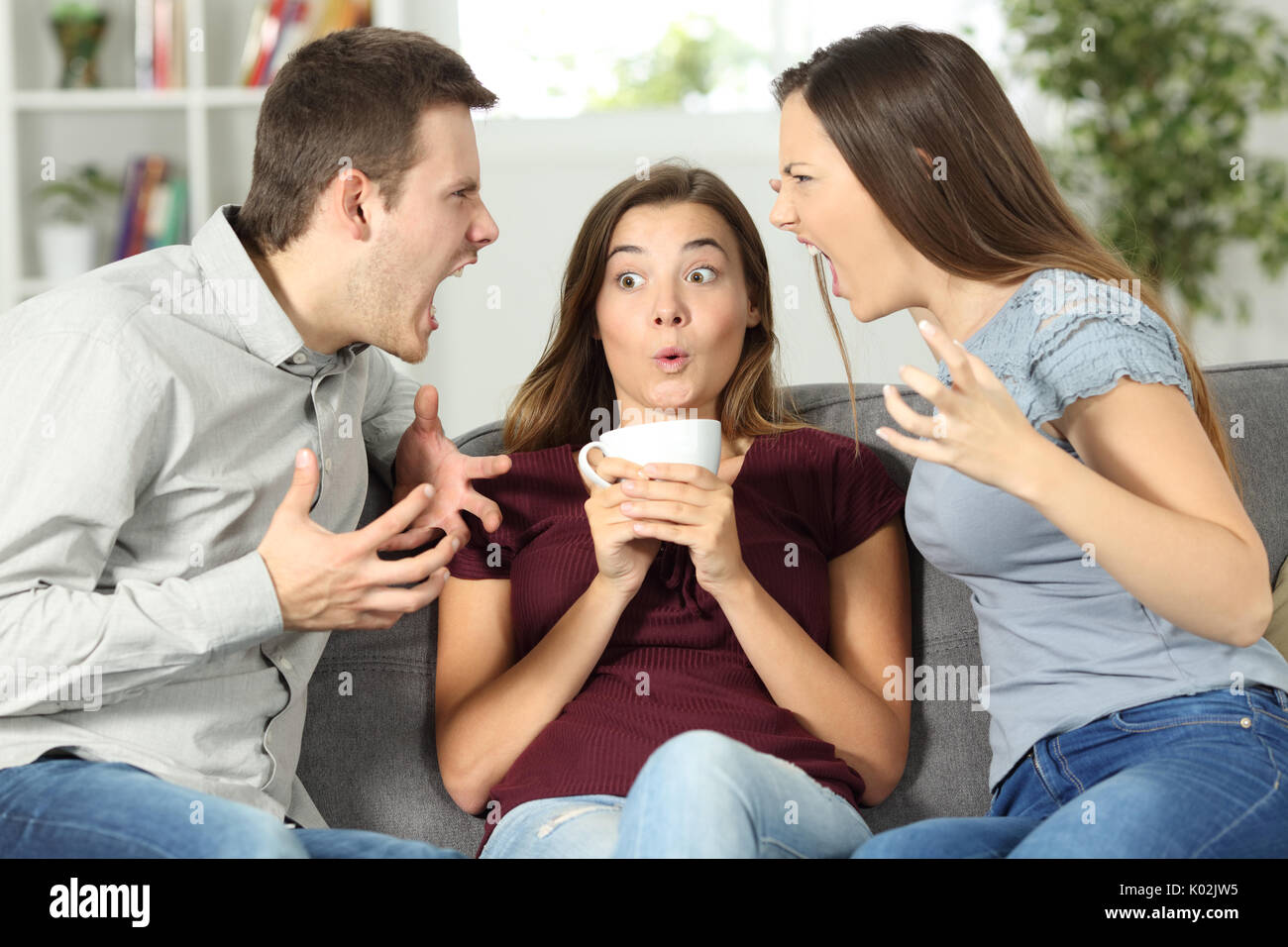 Upset friend in the middle of a couple argument at home Stock Photo