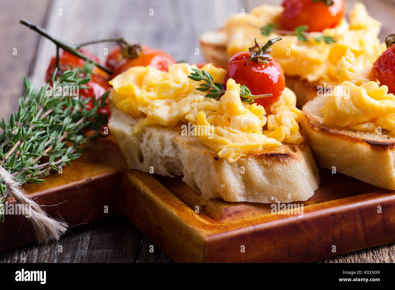 Bruschetta with scrambled eggs and oven roasted cherry tomatoes, delicious summer appetizer Stock Photo