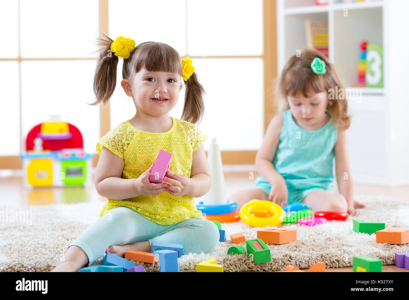 Children playing together. Toddler kids play with blocks. Educational toys for preschool and kindergarten child. Little girls build pyramid toys at home or daycare. Stock Photo