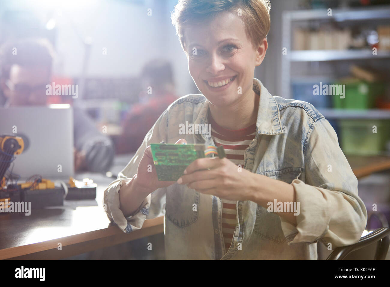 Portrait smiling female engineer assembling circuit board in workshop Stock Photo