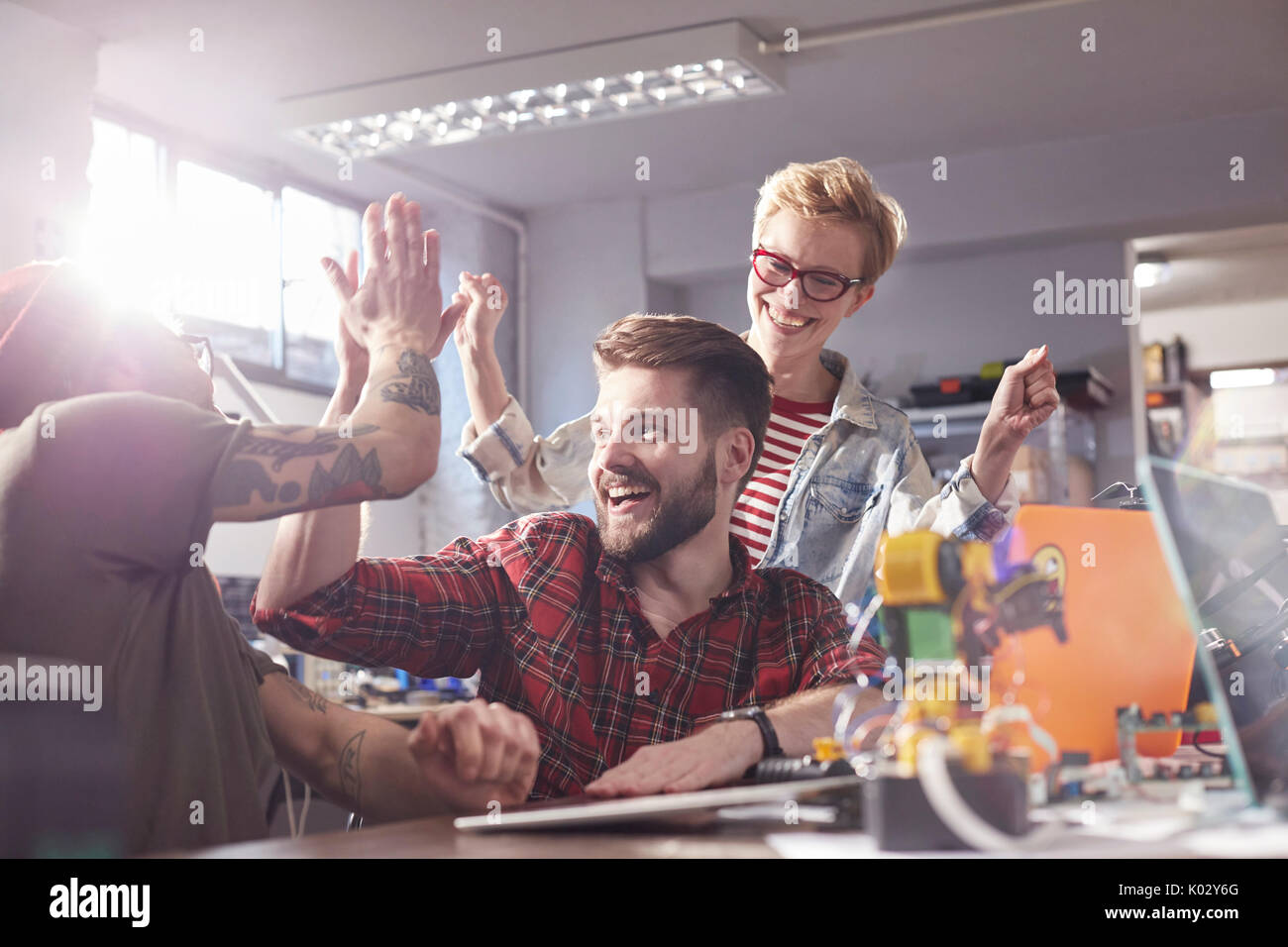 Enthusiastic designers high-fiving, celebrating in workshop Stock Photo