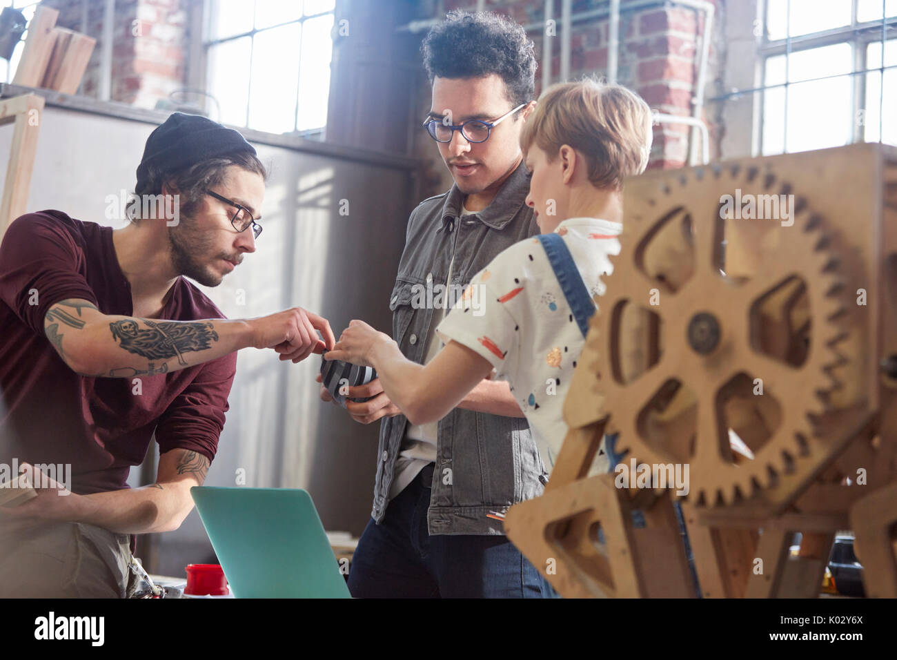 Designers examining and discussing prototype in workshop Stock Photo