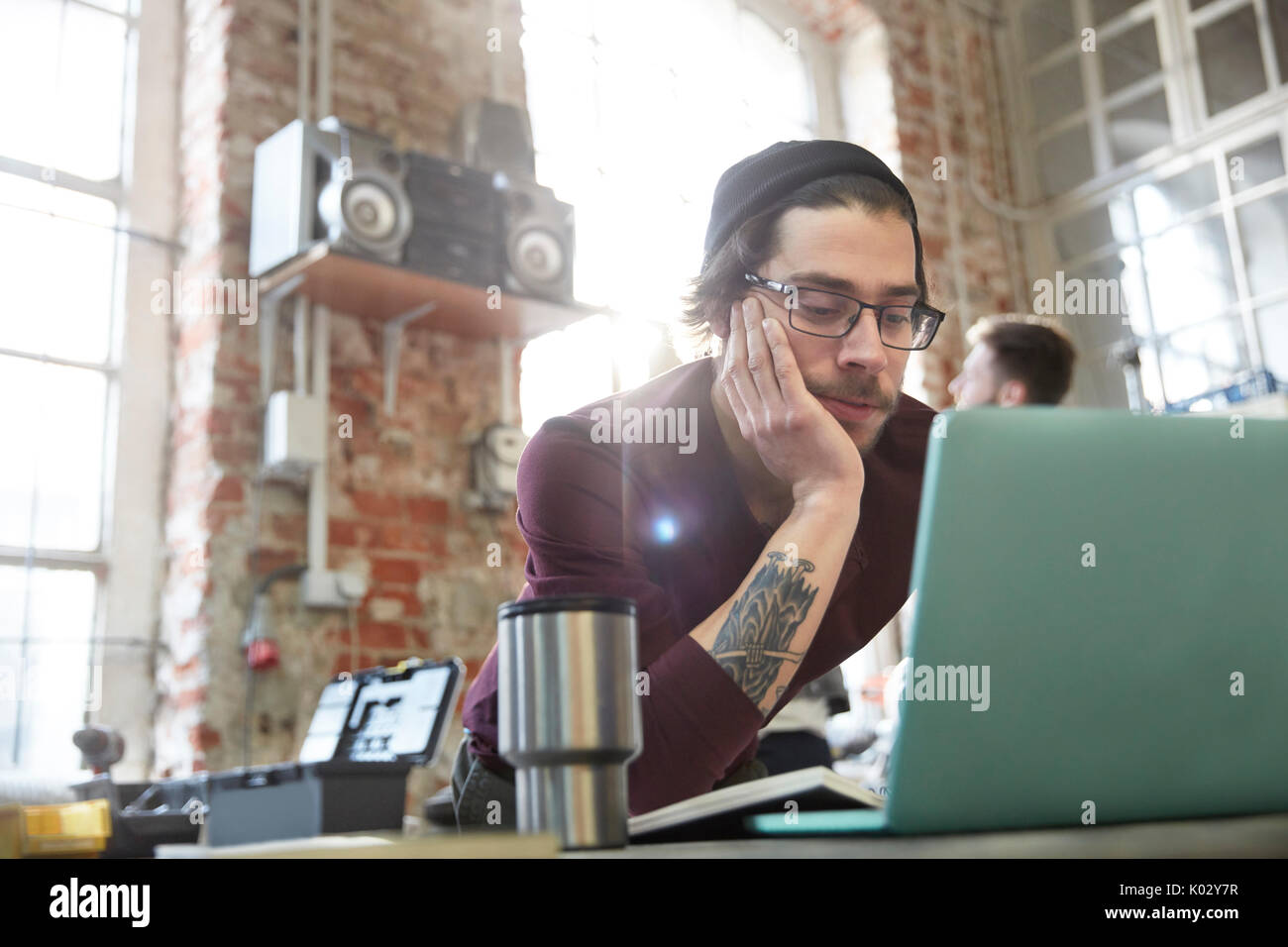 Young male designer using laptop in workshop Stock Photo