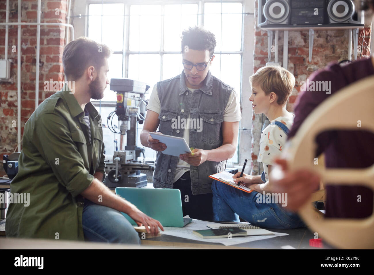 Designers meeting, using clipboard and laptop in workshop Stock Photo