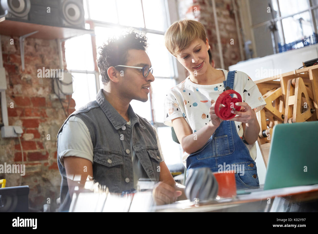 Designers discussing prototype cog in workshop Stock Photo