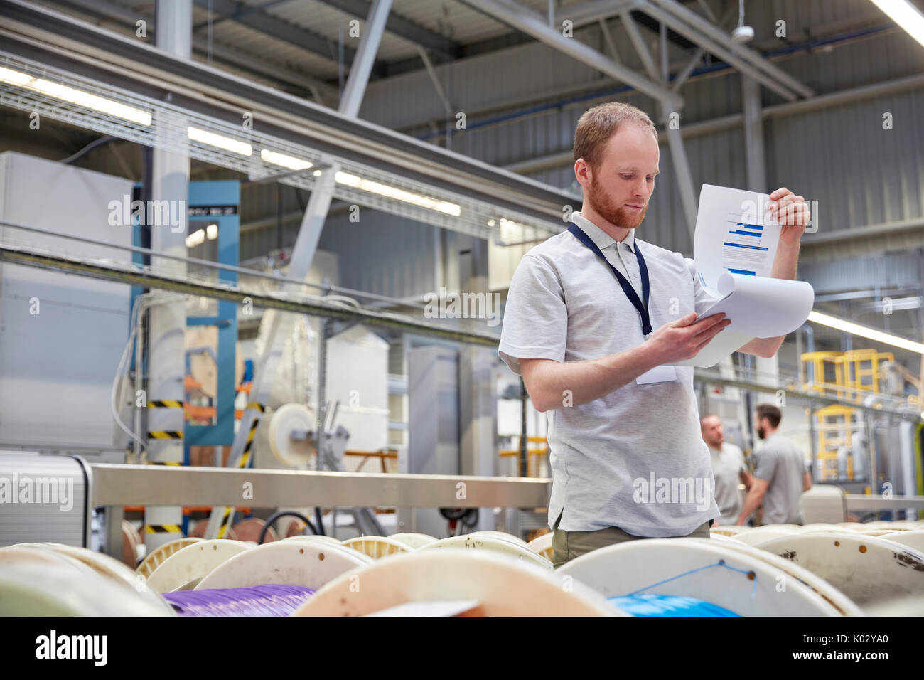 Male supervisor with clipboard checking inventory in fiber optics factory Stock Photo