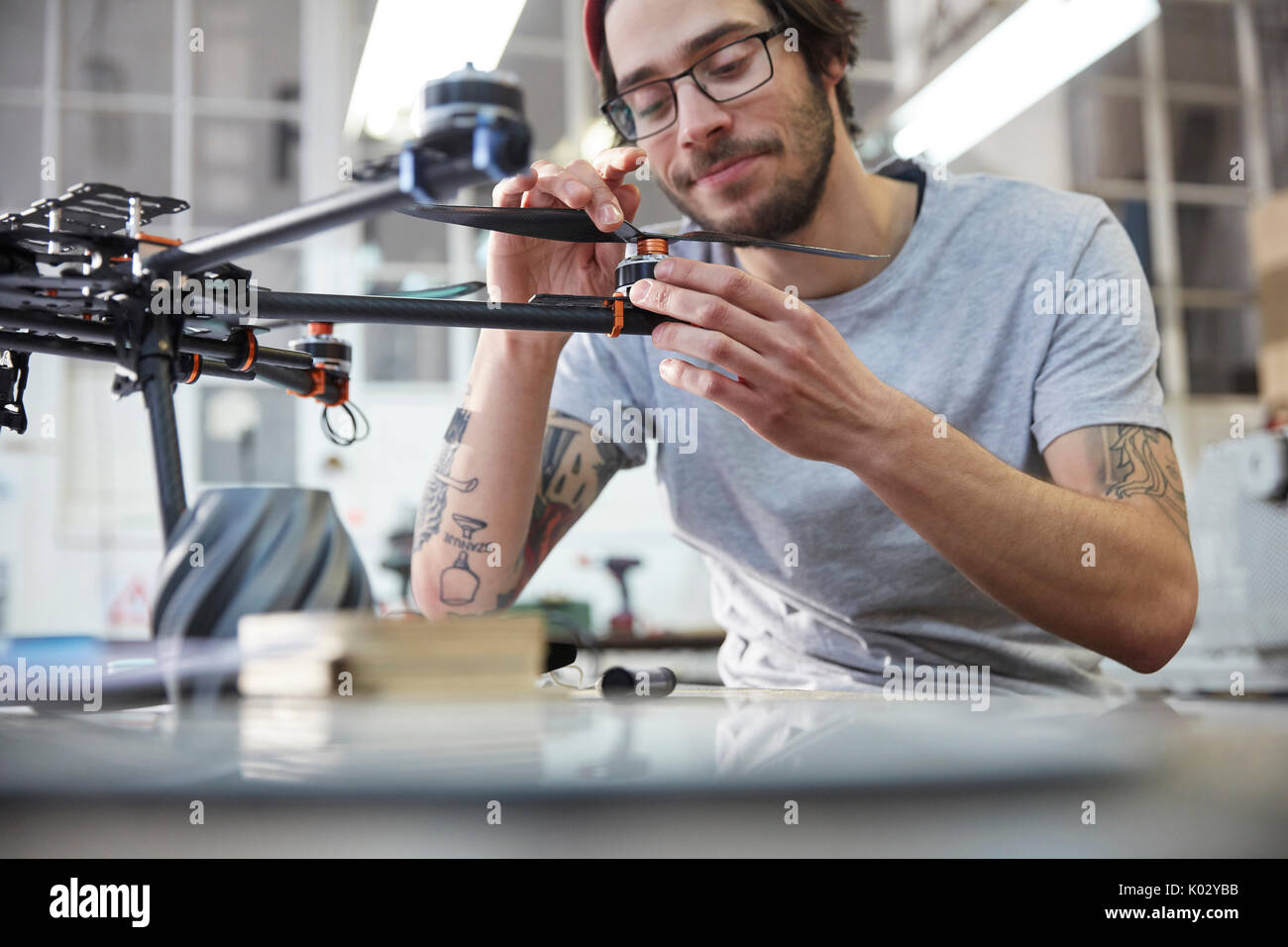 Male designer with tattoos assembling drone in workshop Stock Photo