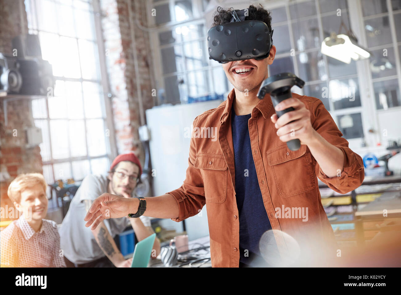 Smiling male computer programmer texting virtual reality simulator glasses and joystick in workshop Stock Photo