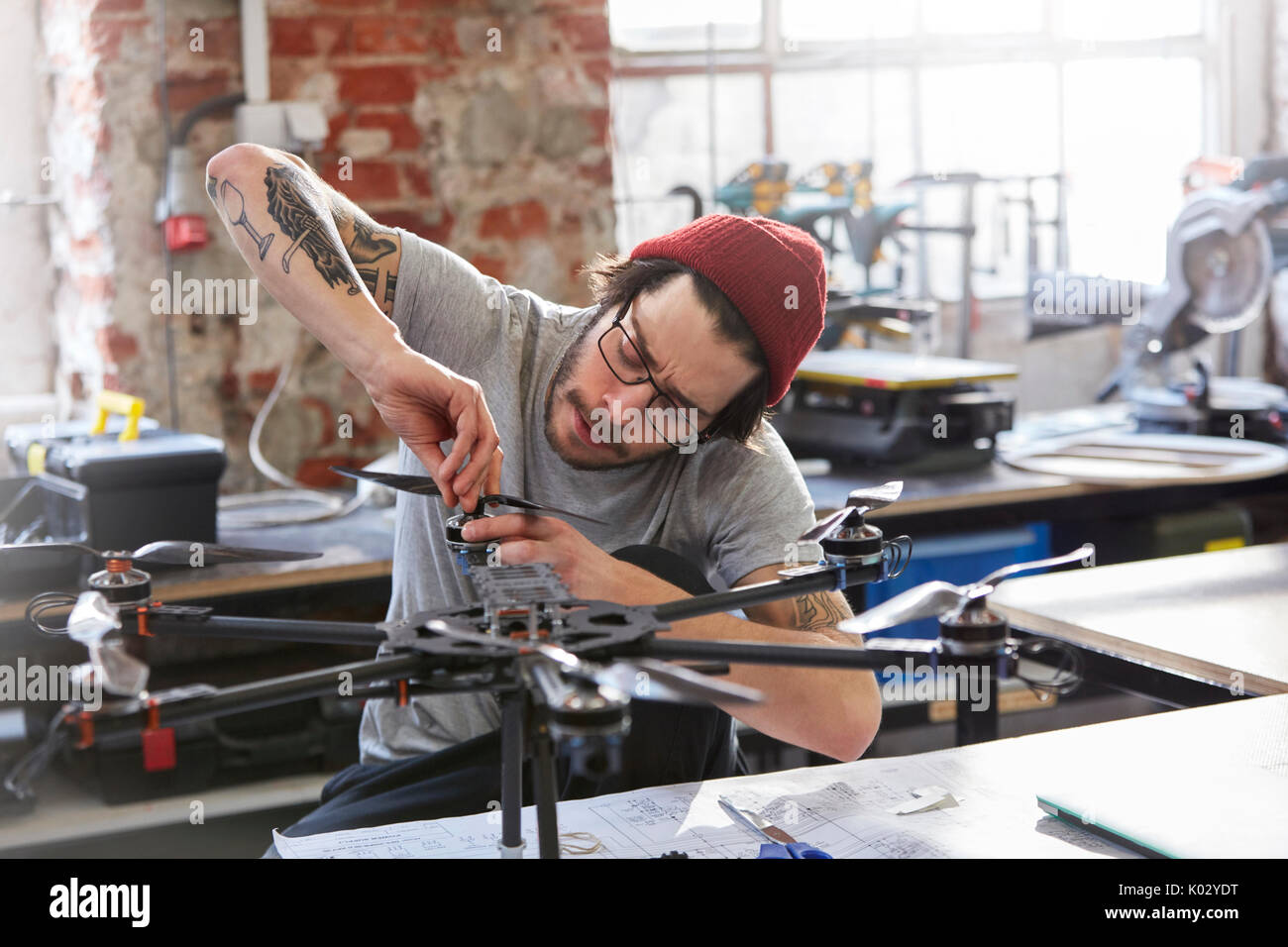 Male designer with tattoos assembling drone in workshop Stock Photo
