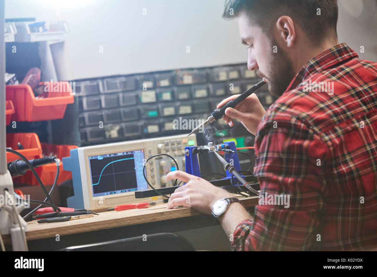 Male engineer assembling electronics, using soldering iron Stock Photo