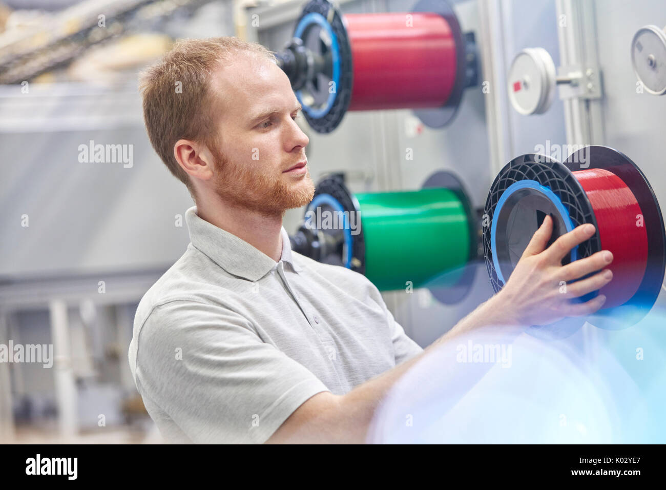 Male worker changing spool in fiber optics factory Stock Photo