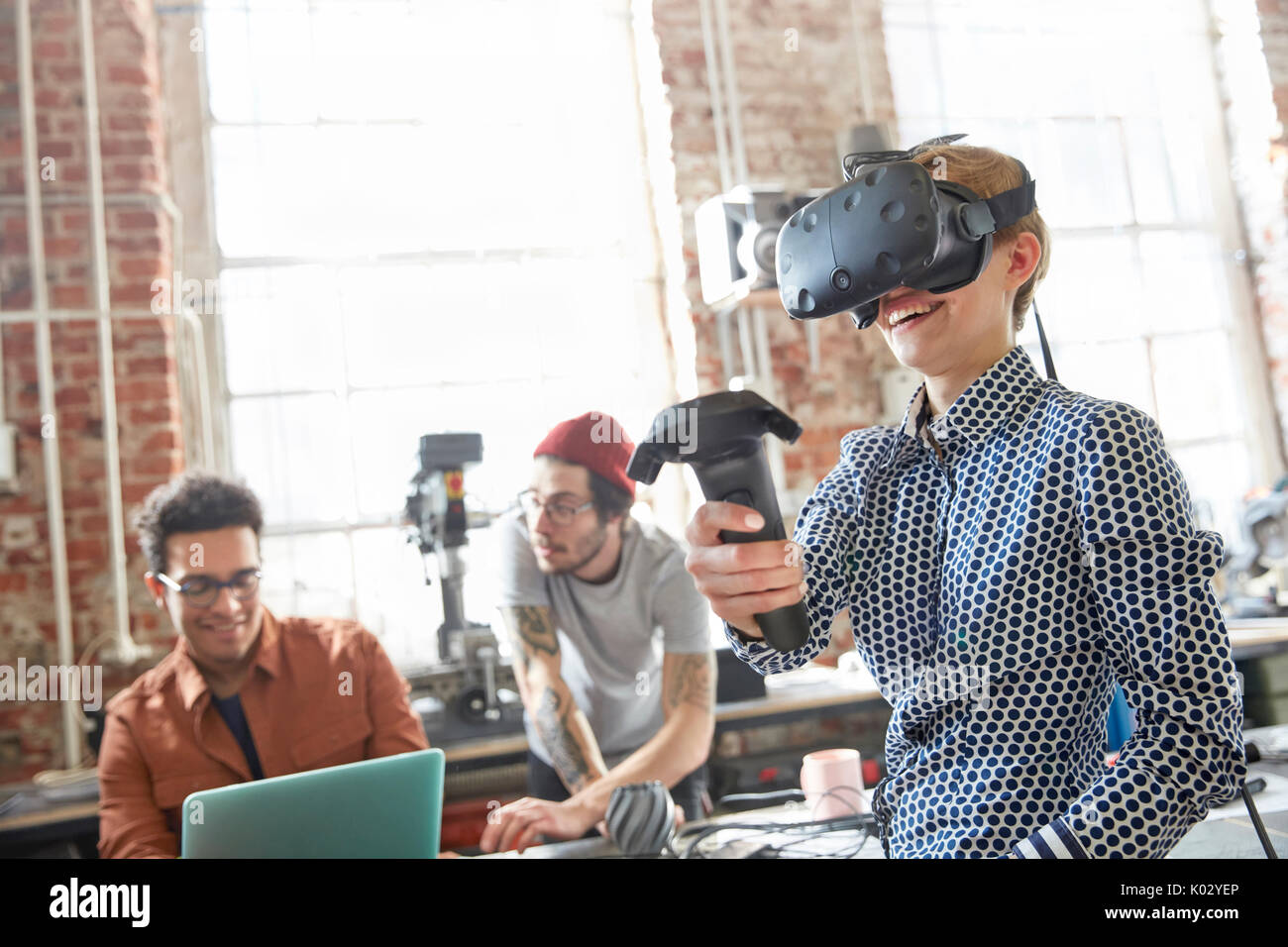 Female designer texting virtual reality simulator glasses and using joystick in workshop Stock Photo