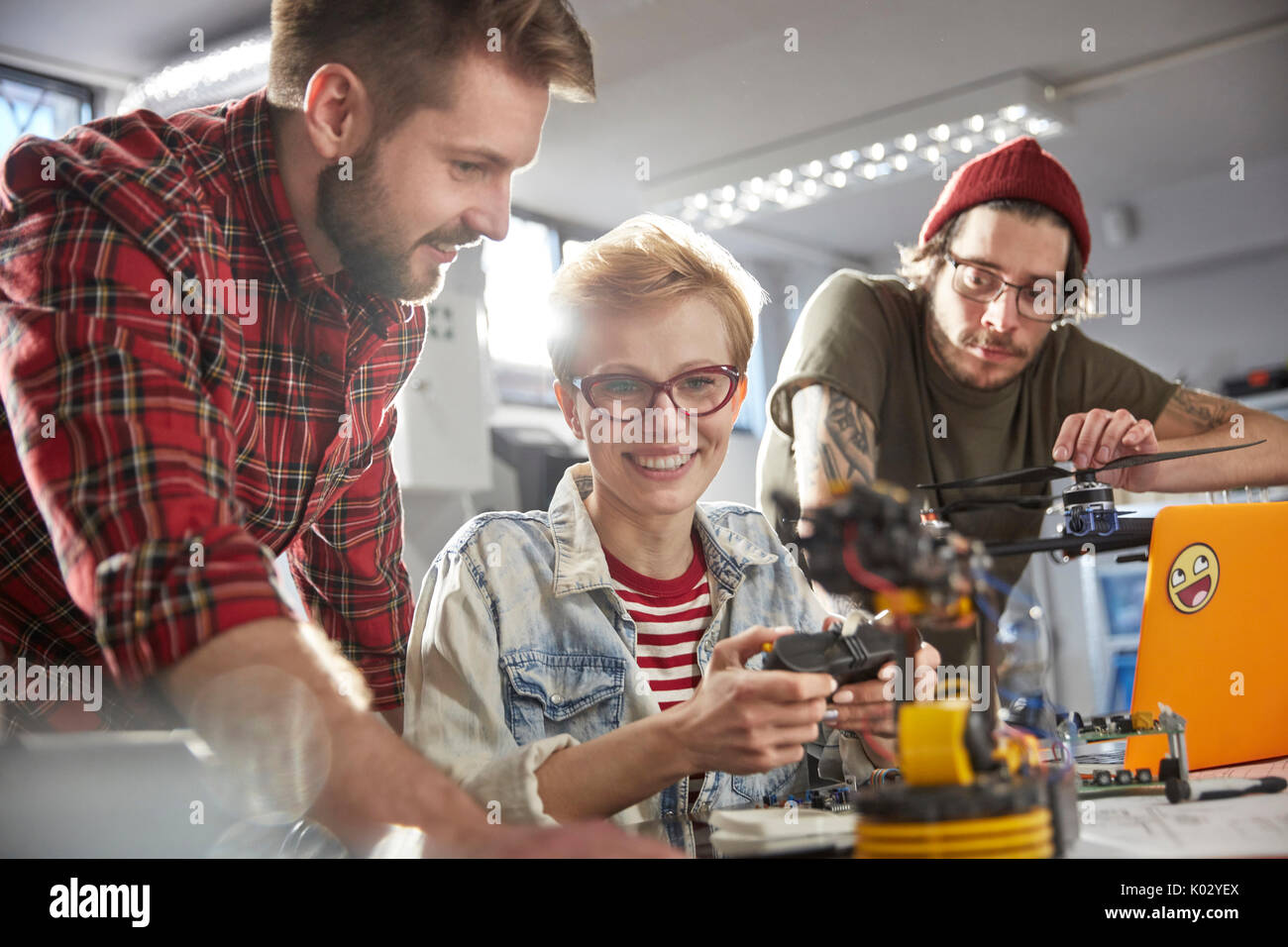 Smiling computer programmers programming robotics Stock Photo - Alamy