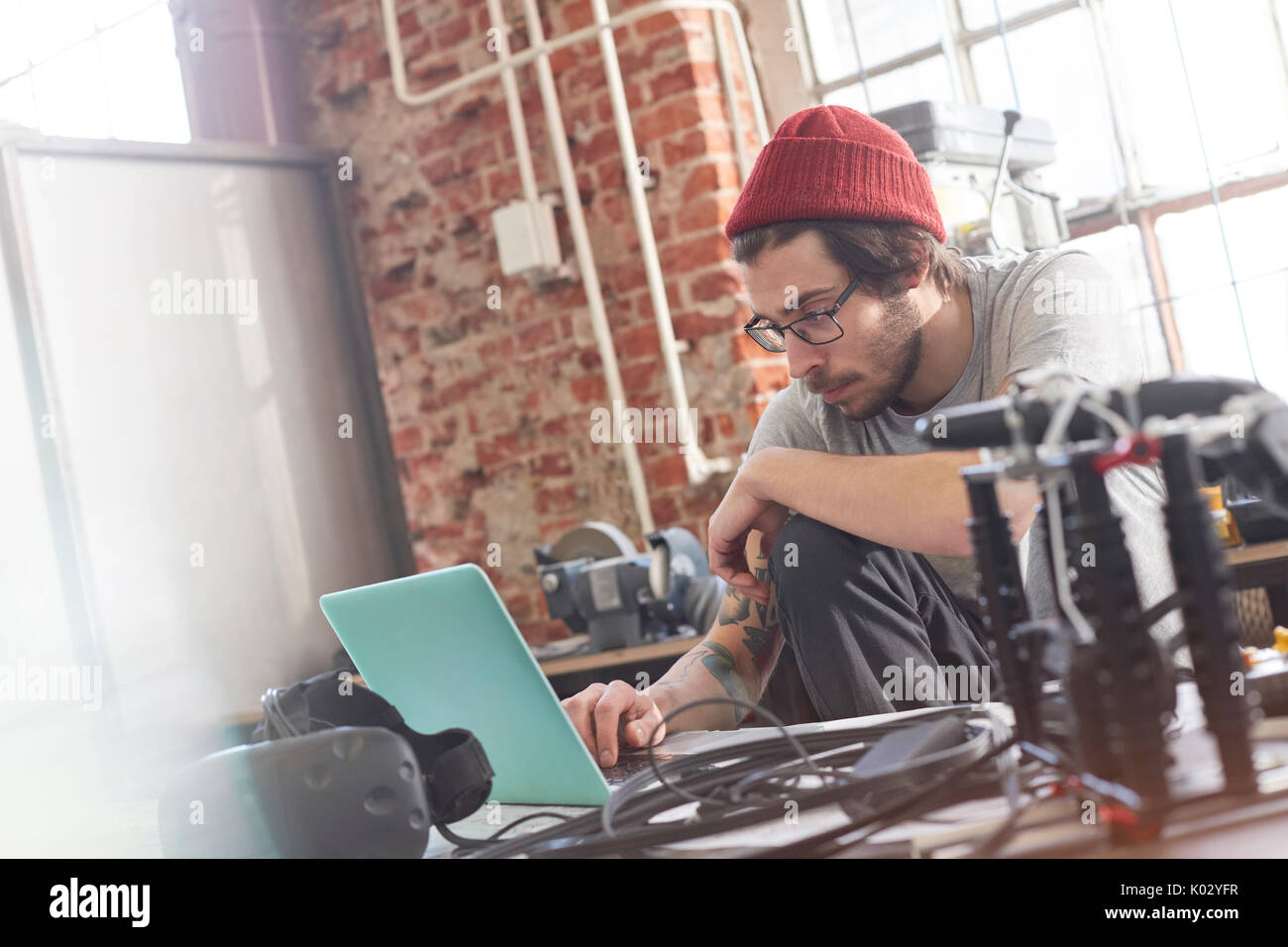 Male computer programmer working at laptop in workshop Stock Photo