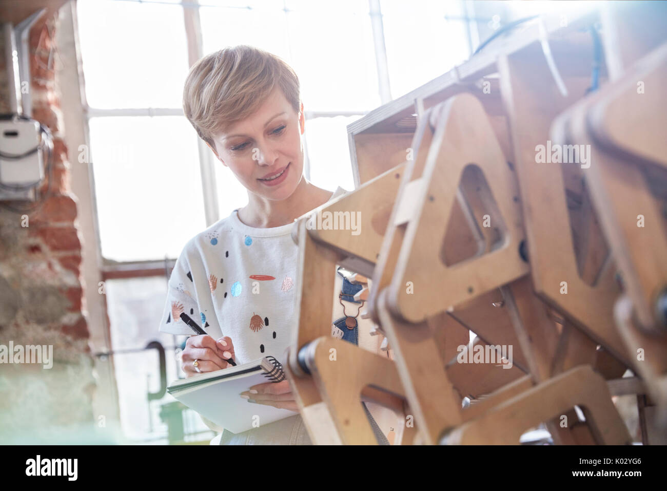 Female designer examining prototype and taking notes Stock Photo