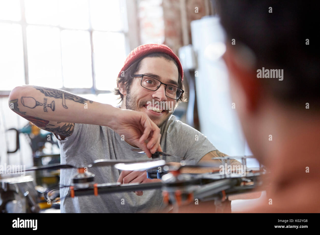 Smiling male designer with tattoos assembling drone Stock Photo