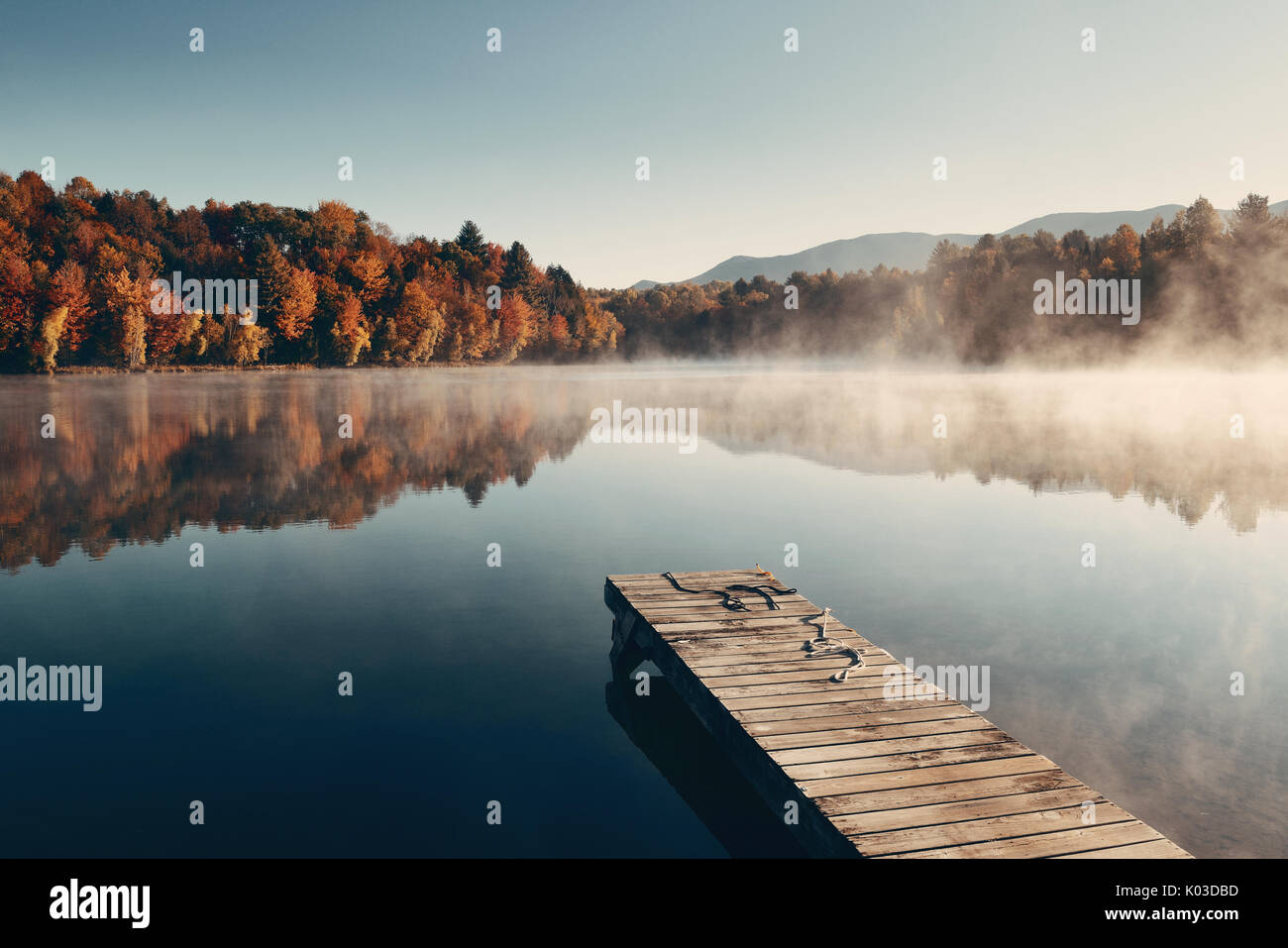 Autumn foliage and fog lake in morning with boat dock Stock Photo - Alamy