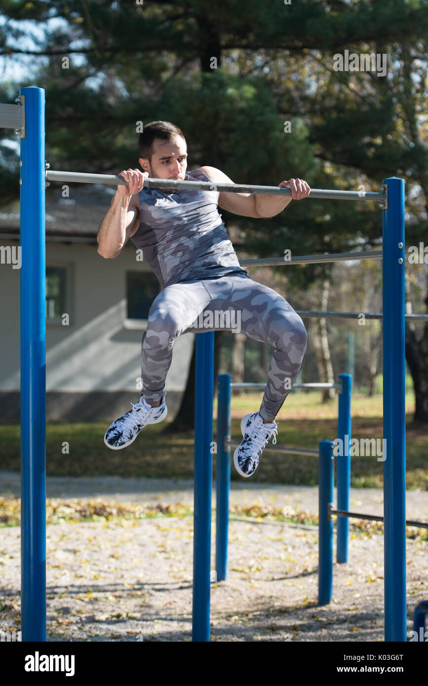 Young Man Doing Crossfit Exercise With Dips Bar in City Park Area Training and Exercising for