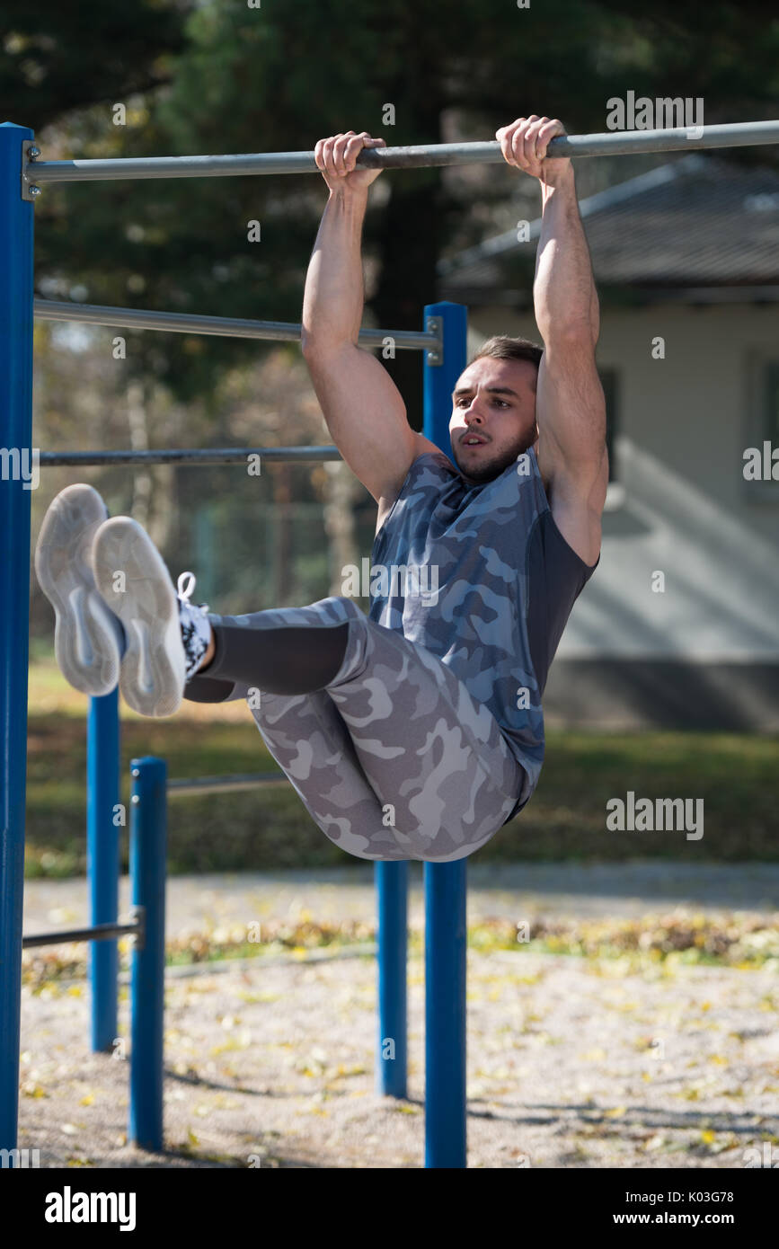 Young Man Doing Crossfit Exercise With Dips Bar in City Park Area Training and Exercising for