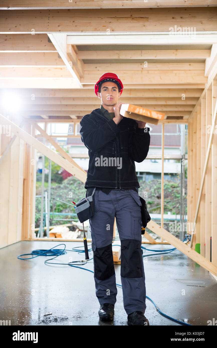 Carpenter Carrying Plank At Construction Site Stock Photo