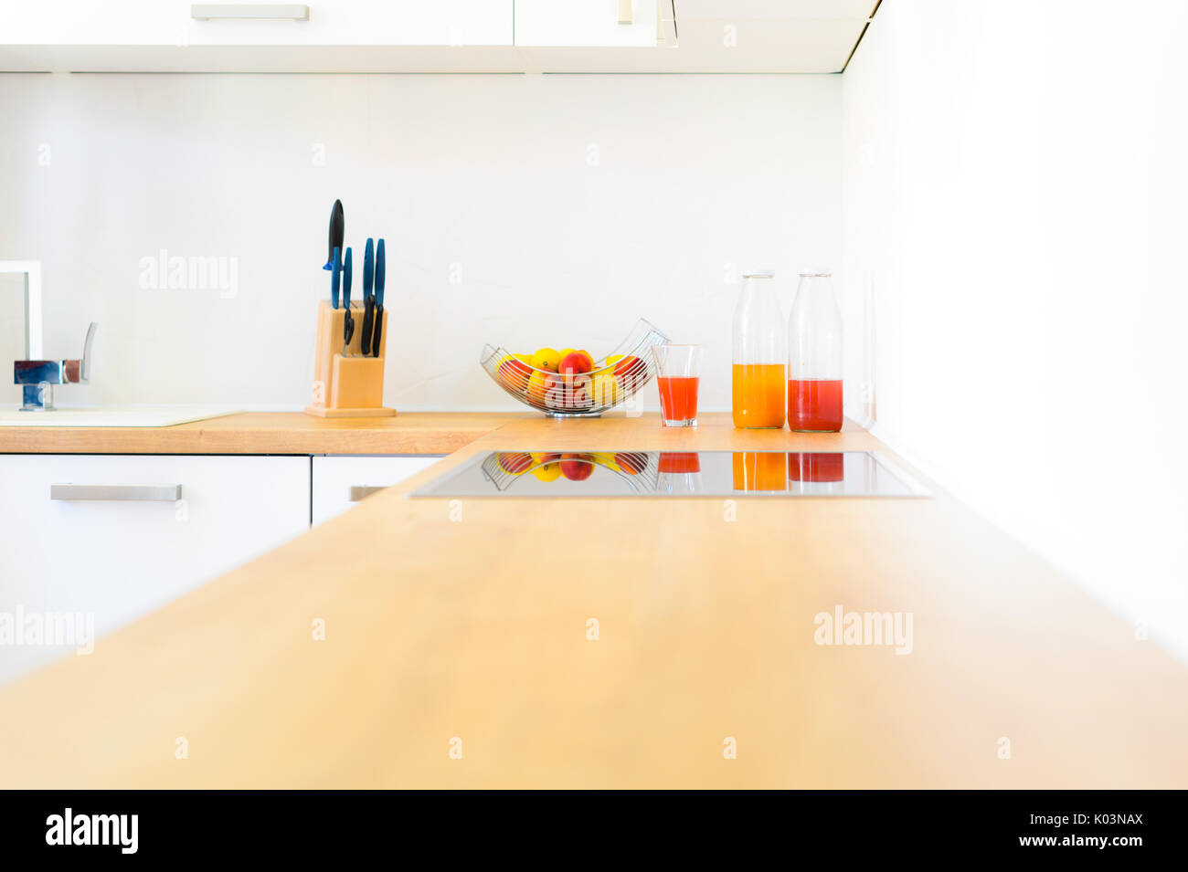 Modern wooden kitchen counter with induction hob, fresh fruit and homemade lemonade Stock Photo