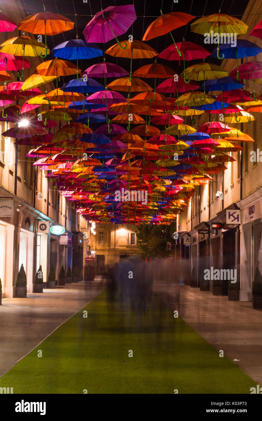 BATH, UK - 19 AUG 2017 Shoppers and umbrellas on St. Lawrence Steet. Public art installation on shopping street with many people walking at night Stock Photo