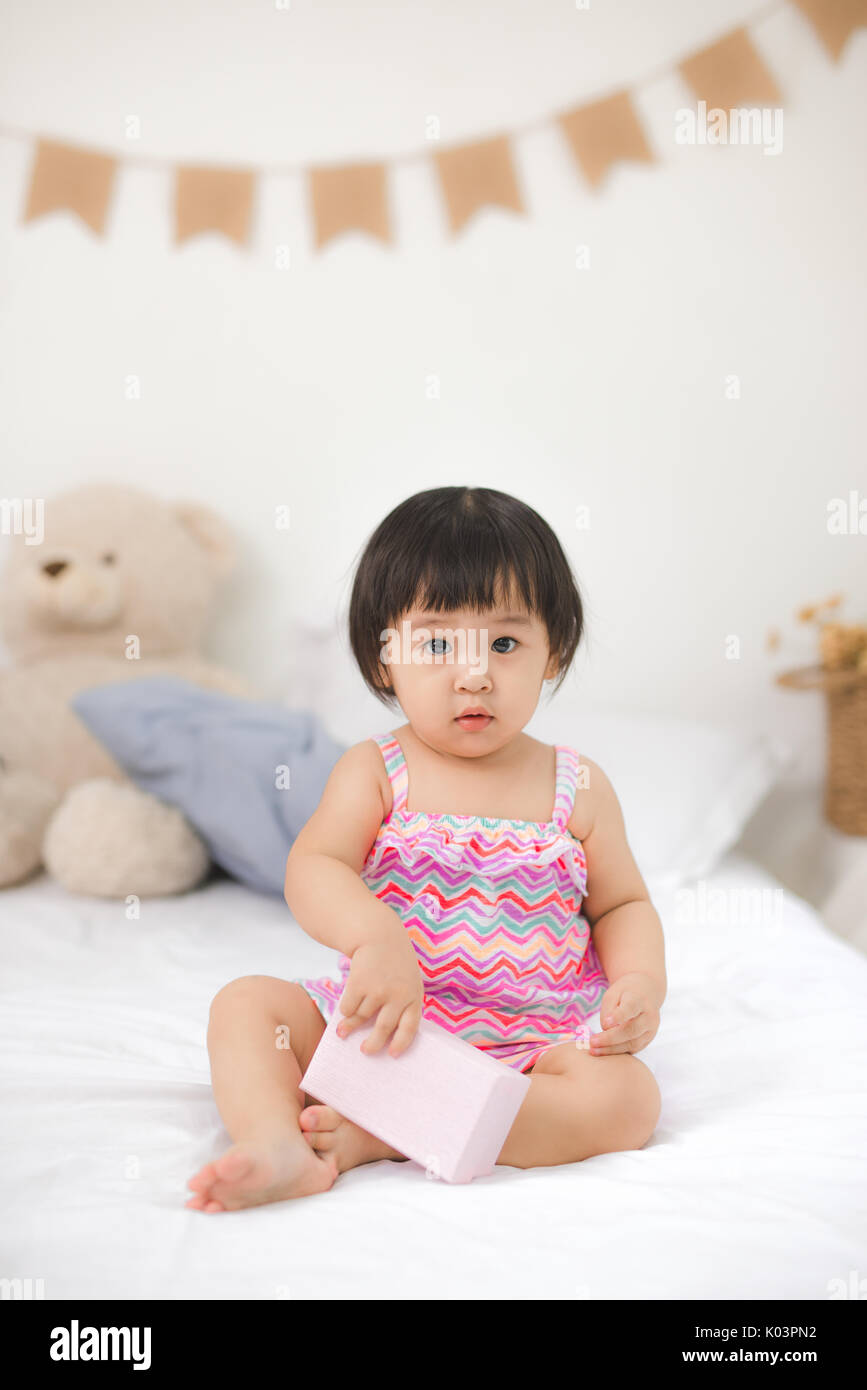Little cute asian baby girl sitting on bed playing Stock Photo