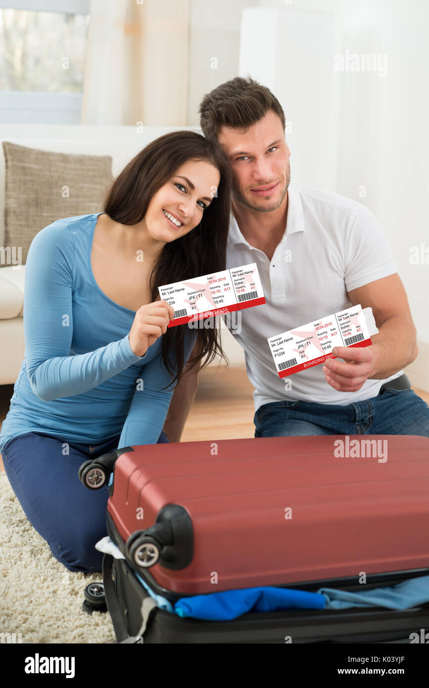 Portrait Of Happy Young Couple Packing Luggage Showing Boarding Pass ...