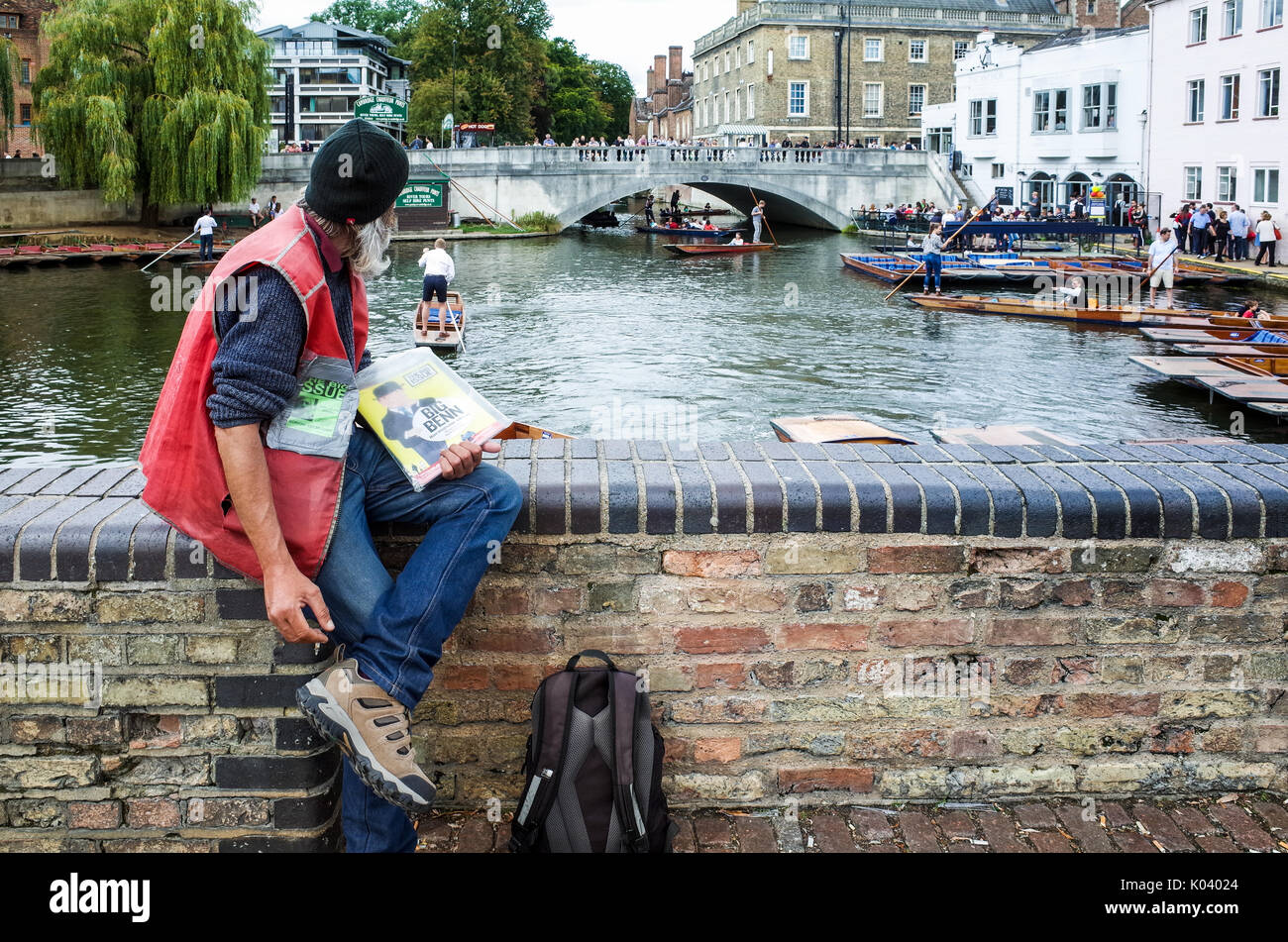Big Issue Seller looks out over punts on the River Cam in Cambridge UK Stock Photo