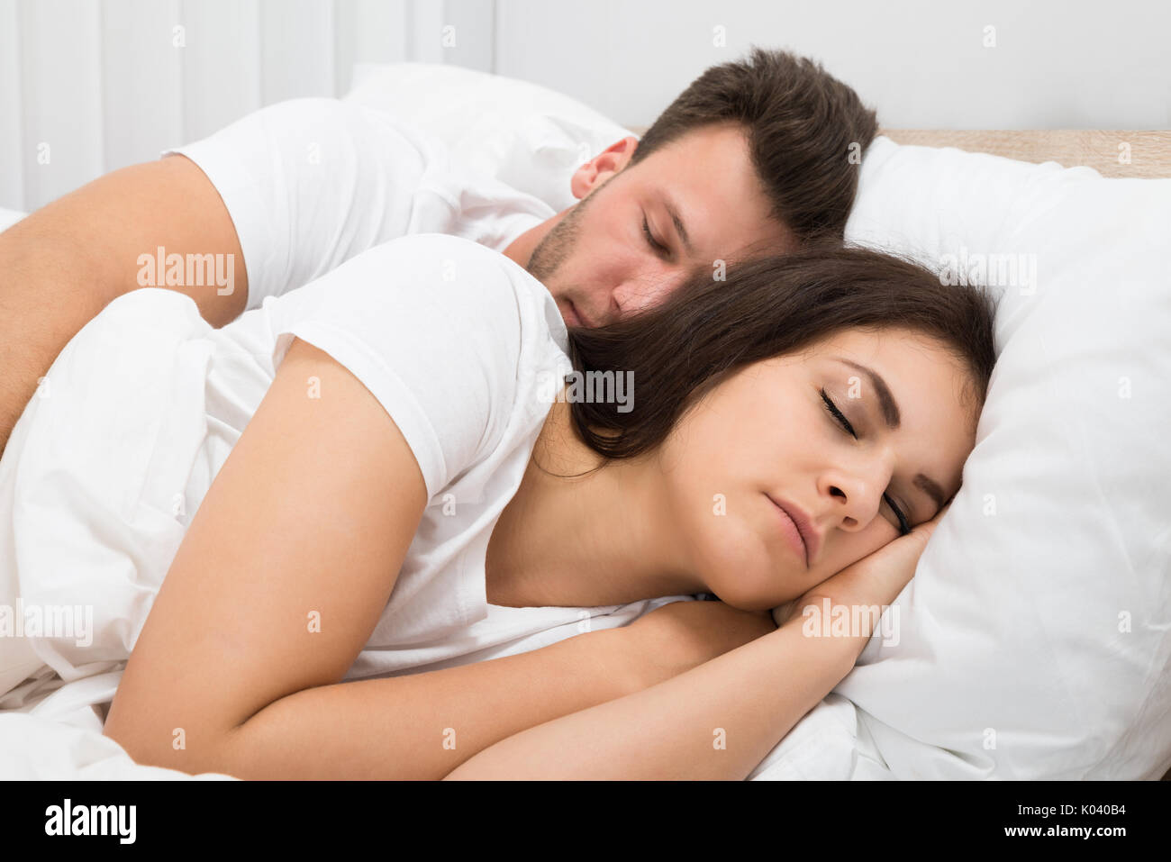 Portrait Of Young Couple Sleeping On Bed Stock Photo
