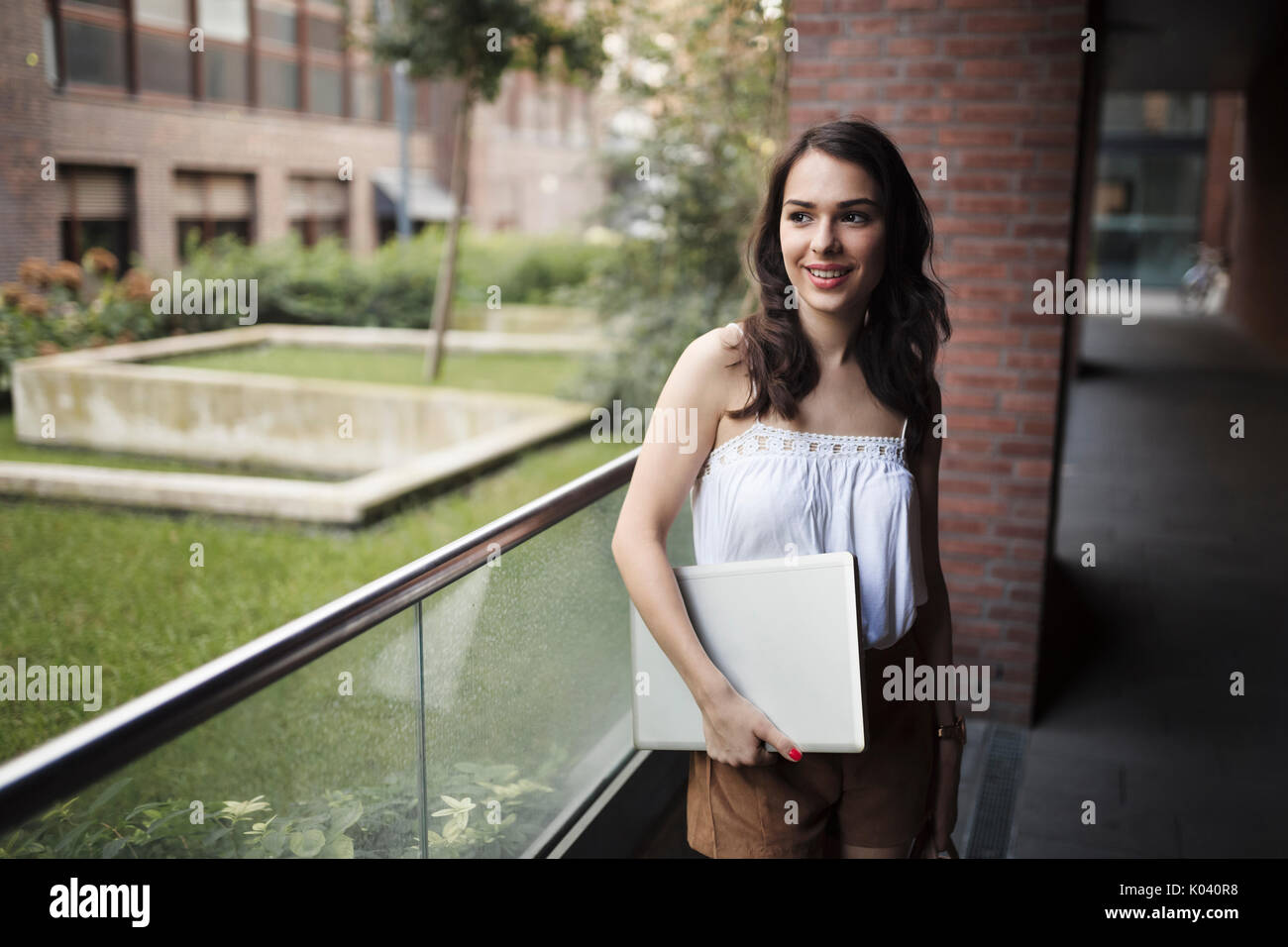 Portrait of young smiling woman holding laptop Stock Photo - Alamy