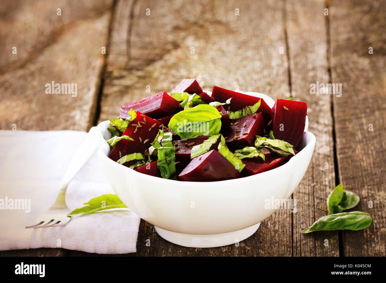 Beetroot chopped for salad with basil and dill seeds in bowl on rustic wooden table Stock Photo