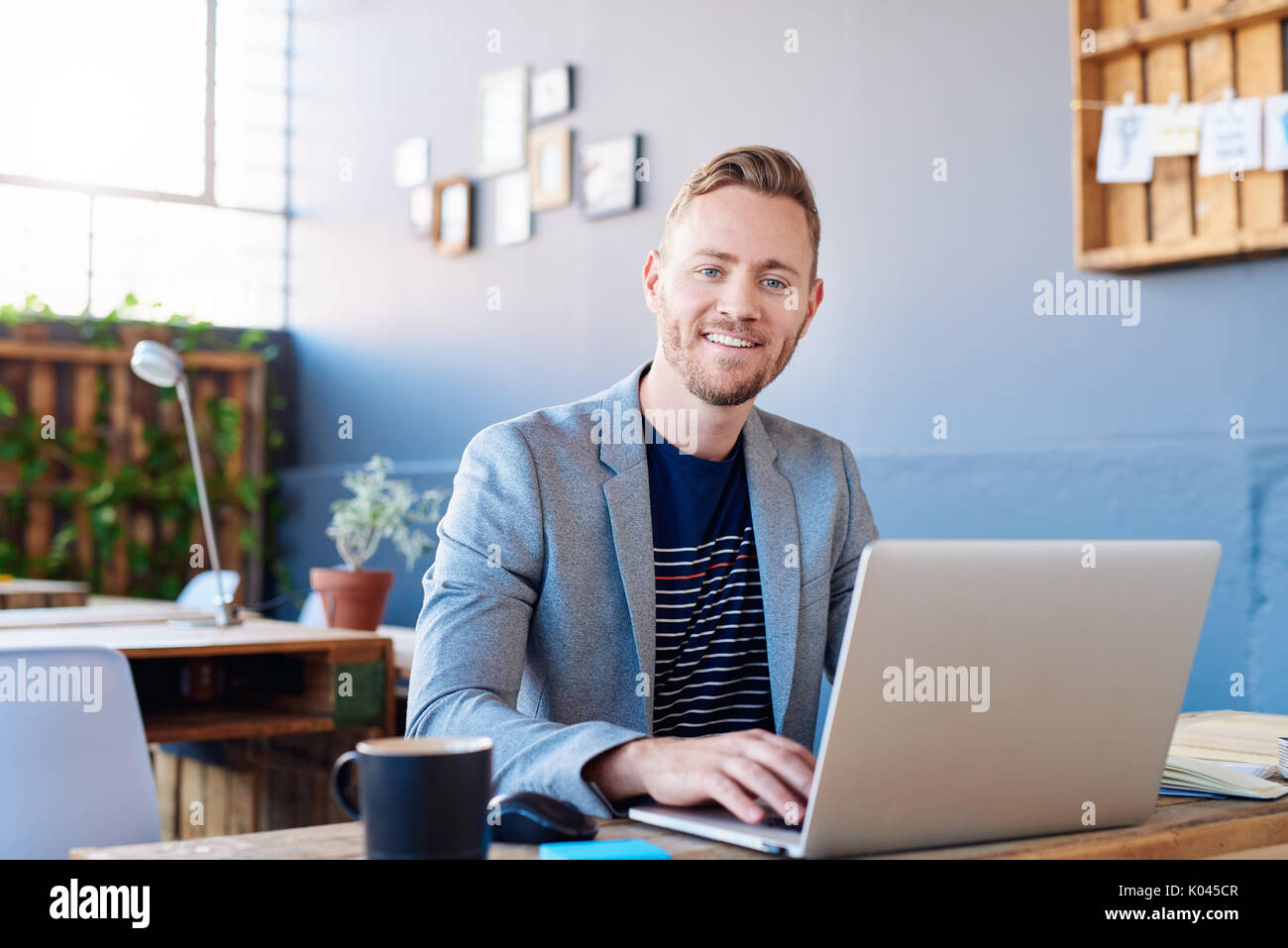 Smiling young businessman working on a laptop in an office Stock Photo