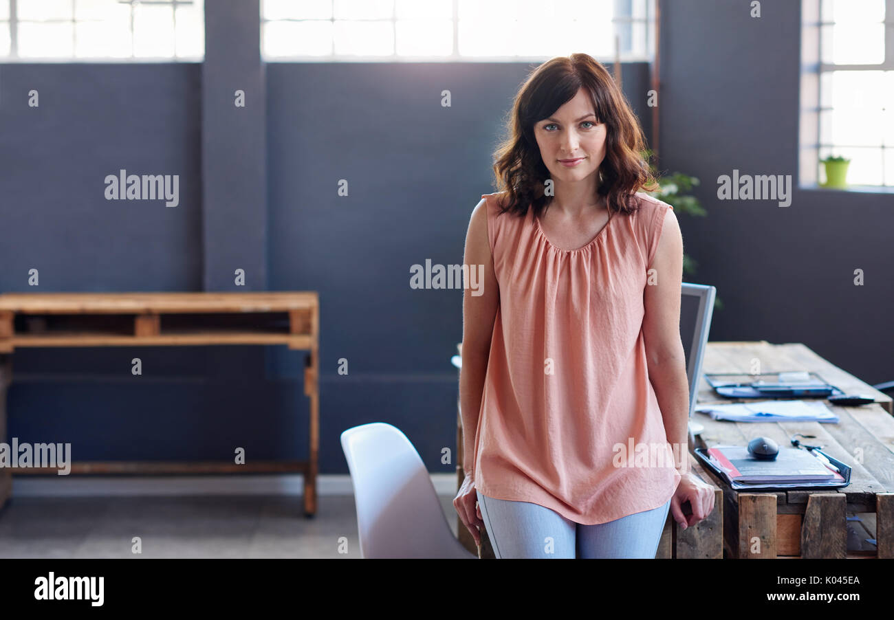 Focused young businesswoman leaning on a desk in an office   Stock Photo