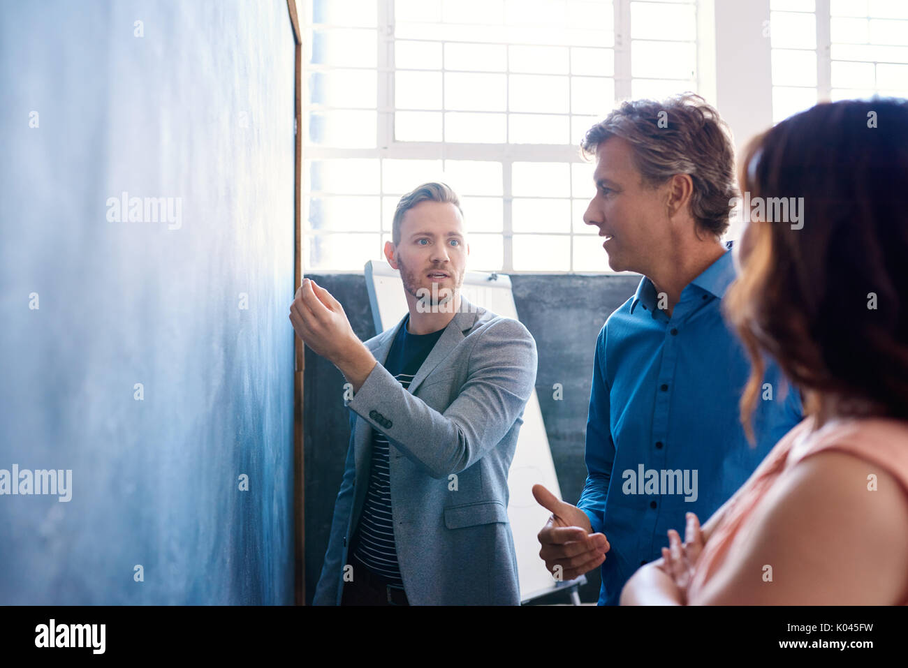 Focused work colleagues brainstorming on a chalkboard in an office Stock Photo