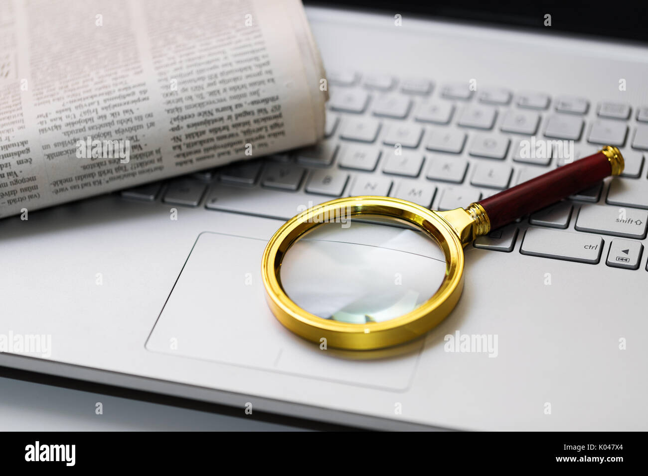 information search concept. newspaper and magnifying glass on keyboard Stock Photo
