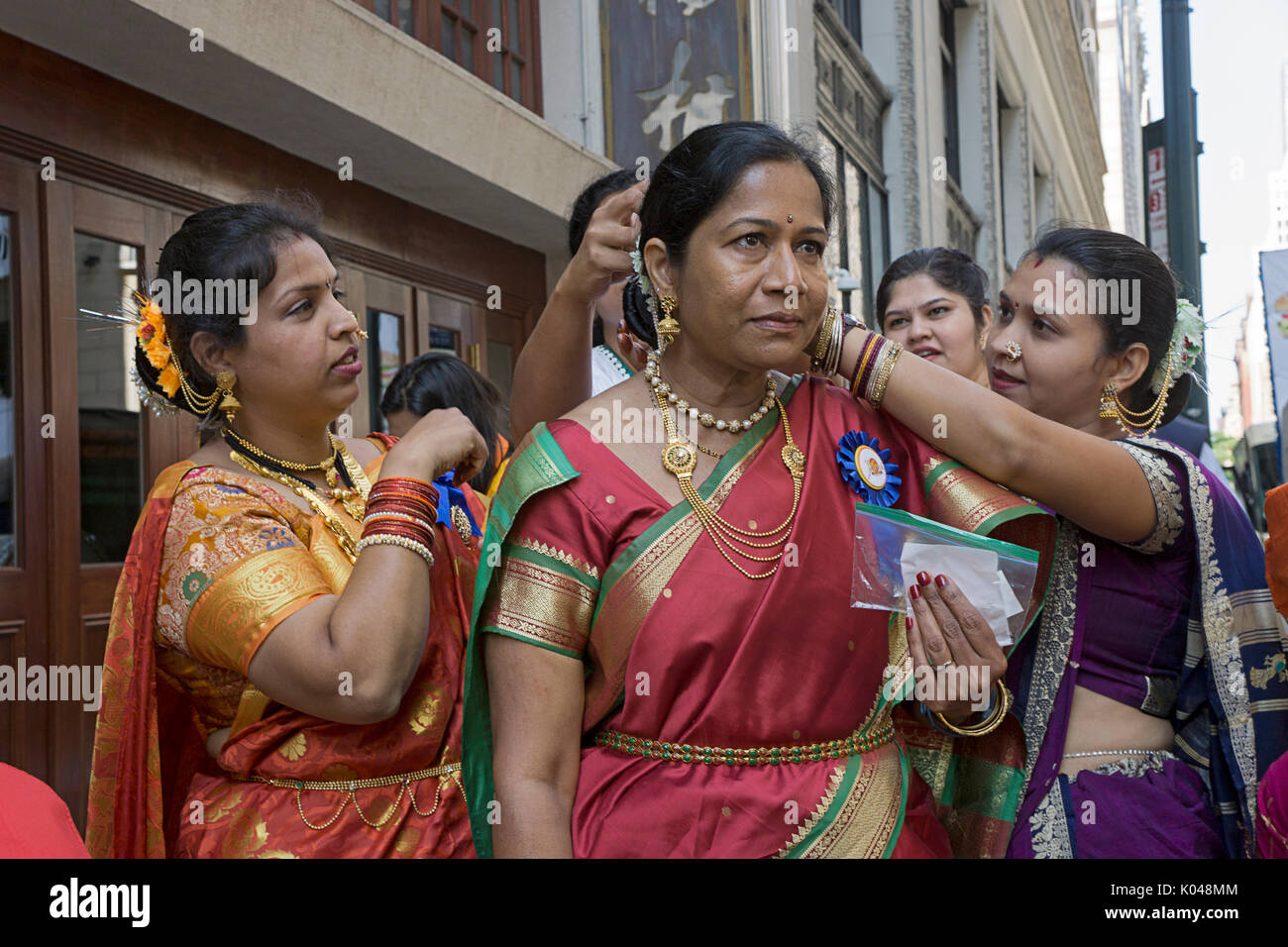 Indian women adjust an older marcher's costume outfit just prior to the start of the 2017 India Day Parade in Manhattan, New York City. Stock Photo