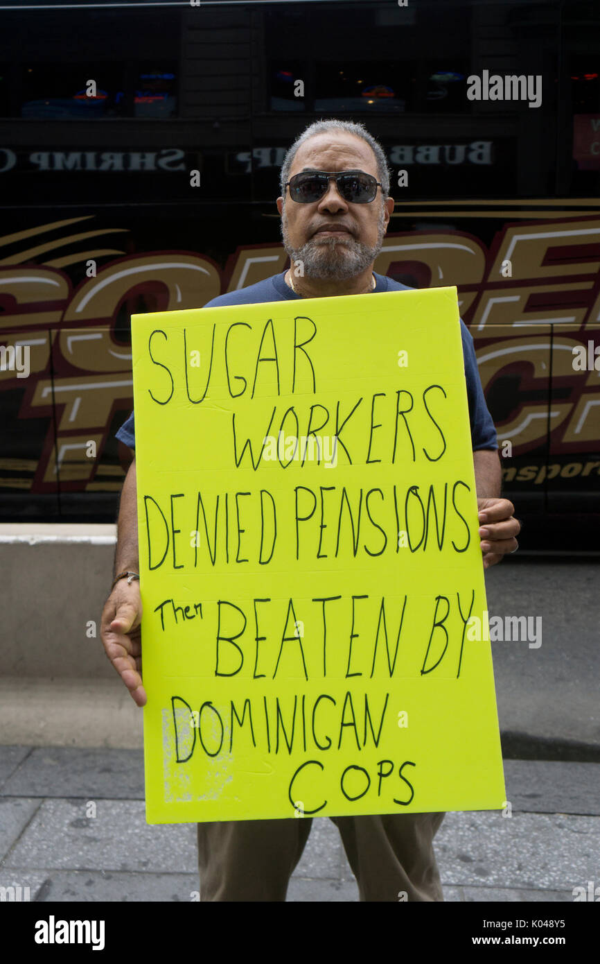 A Latin American man in Times Square holding a sign protesting the treatment of sugar workers in the Dominican Republic by the Dominican police. Stock Photo