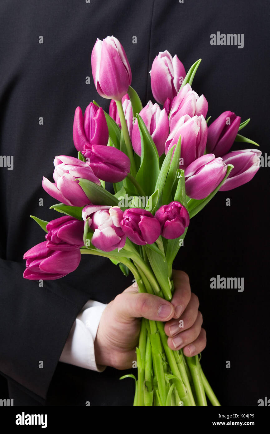 Close up of man holding a bunch of flowers behind his back. Stock Photo