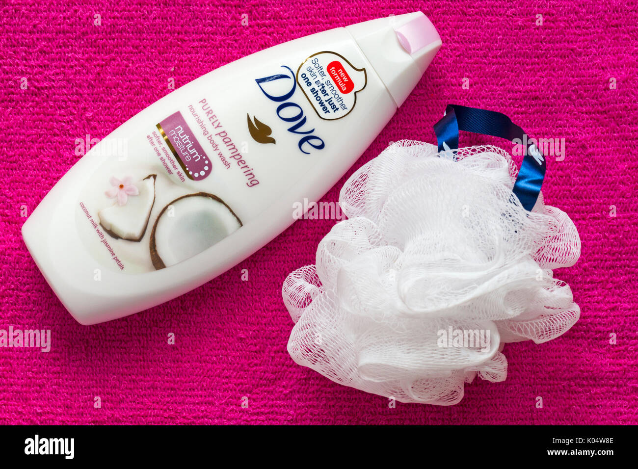 bottle of Dove purely pampering nourishing body wash with shower puff on pink towel Stock Photo