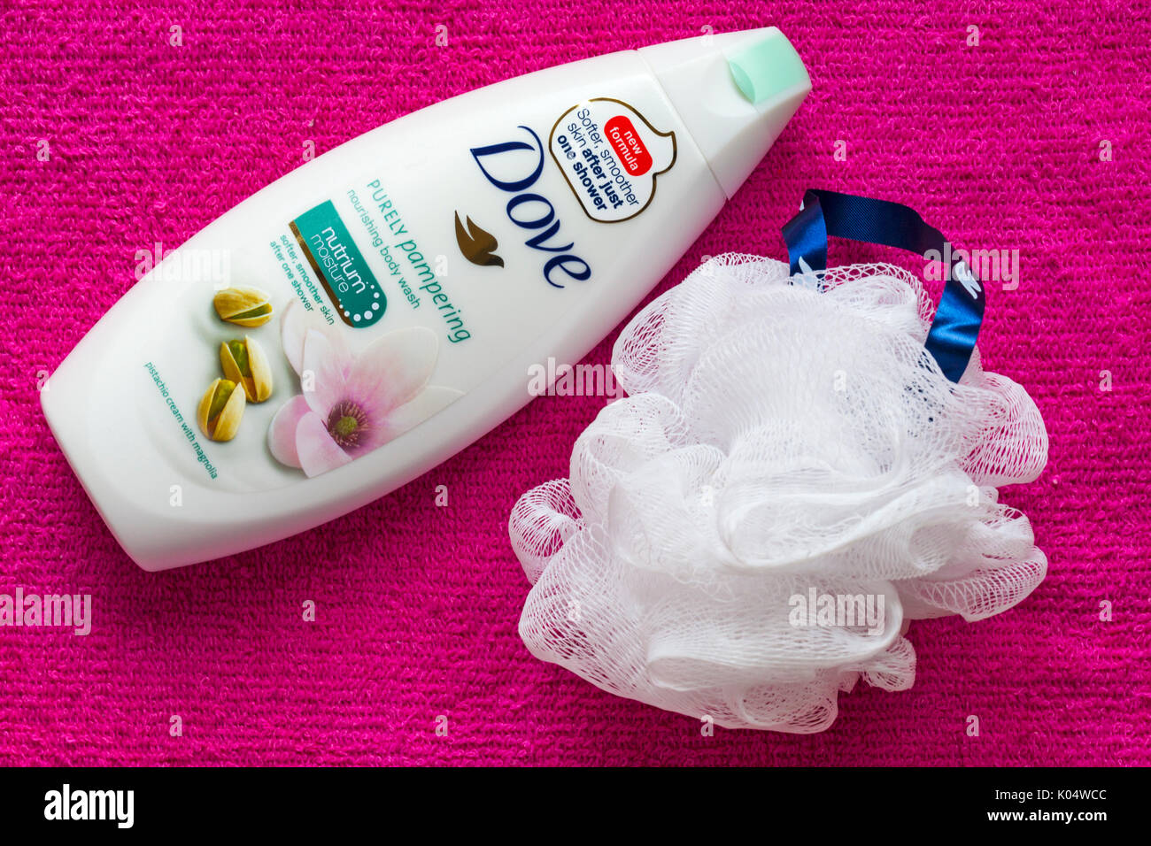 bottle of Dove purely pampering nourishing body wash with shower puff on pink towel Stock Photo