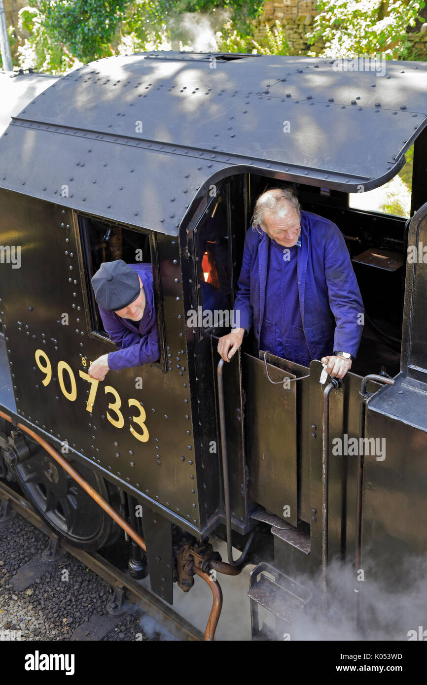 Driver and stoker in the cab of steam locomotive 90733 at Haworth Railway Station, Keighley and Worth Valley Railway, Haworth, West Yorkshire, England. Stock Photo