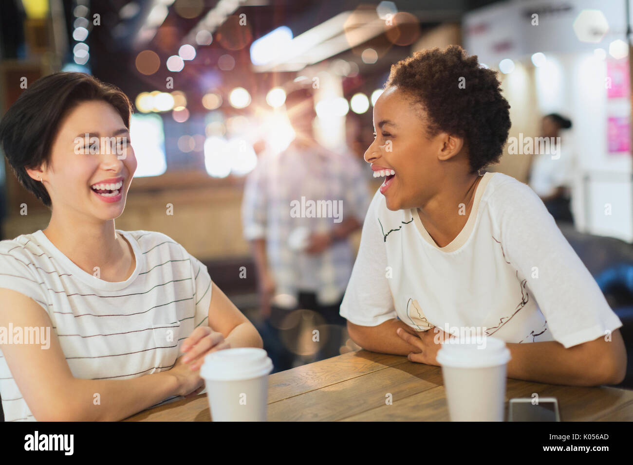 Laughing young women drinking coffee at cafe Stock Photo