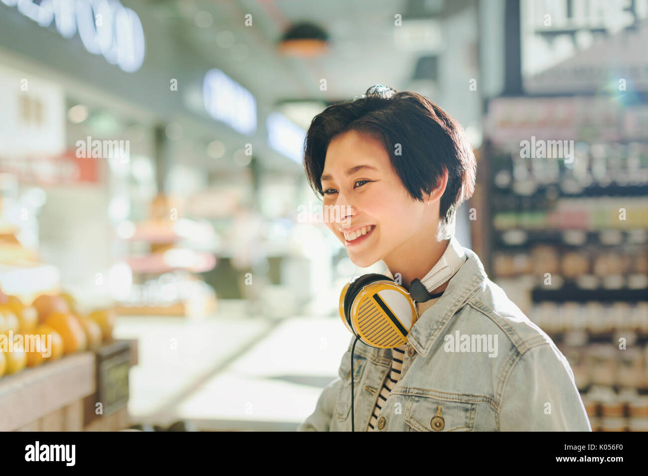 Smiling young woman with headphones grocery shopping in market Stock Photo